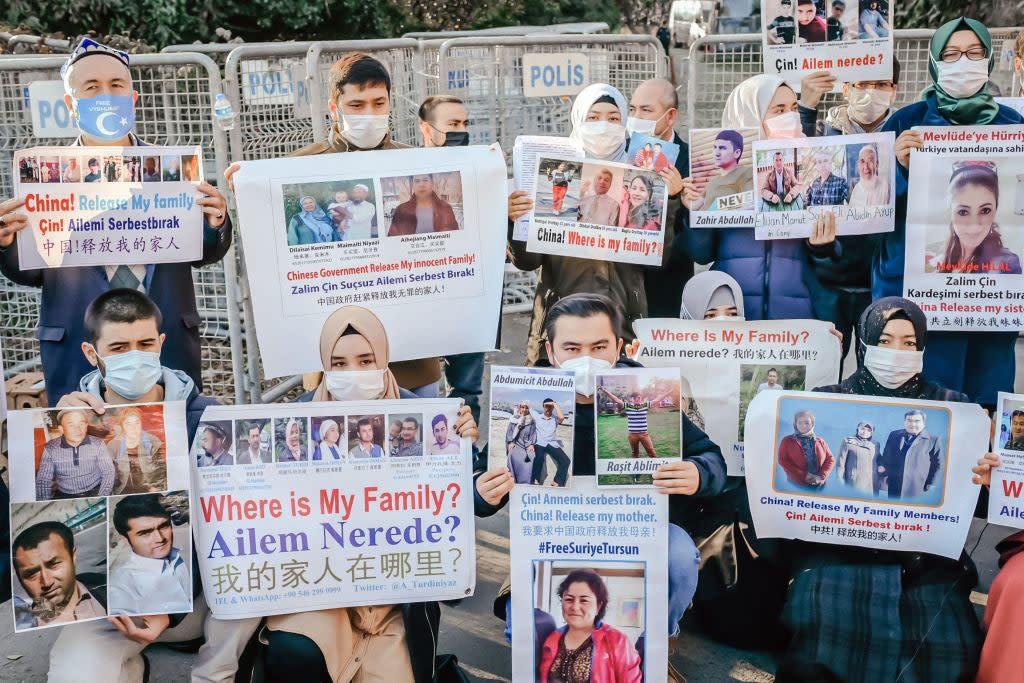 <p>Members of the Muslim Uighur community hold placards as they demonstrate over the whereabouts of family members</p> (AFP via Getty Images)