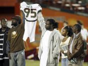 FILE - In this Nov. 23, 2006, file photo, Bryan Pata's family hold up his jersey at the beginning of an NCAA college football game between Miami and Boston College at the Orange Bowl in Miami. Rashaun Jones, 35, of Lake City, a former University of Miami football player was arrested Thursday, Aug. 19, 2021, in connection with the 2006 fatal shooting of his teammate Bryan Pata. Pata, a 22-year-old, 6-foot-4, 280-pound defensive lineman, was shot several times outside of his Kendall, Fla., apartment the night of Nov. 7, 2006. (AP Photo/Luis M. Alvarez, File)