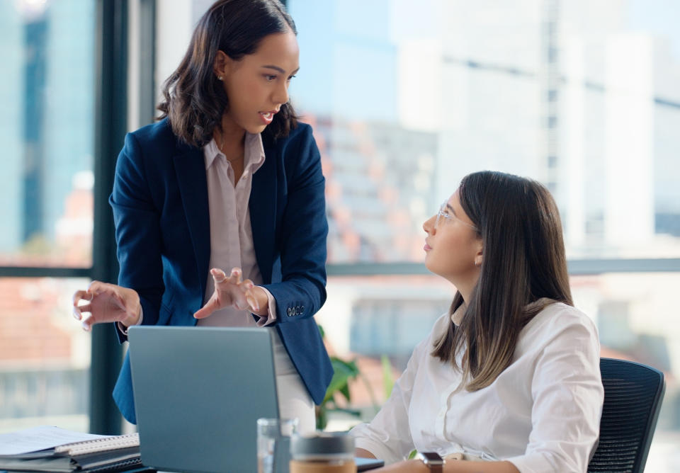 Two professionals engaged in a discussion next to a laptop on a desk