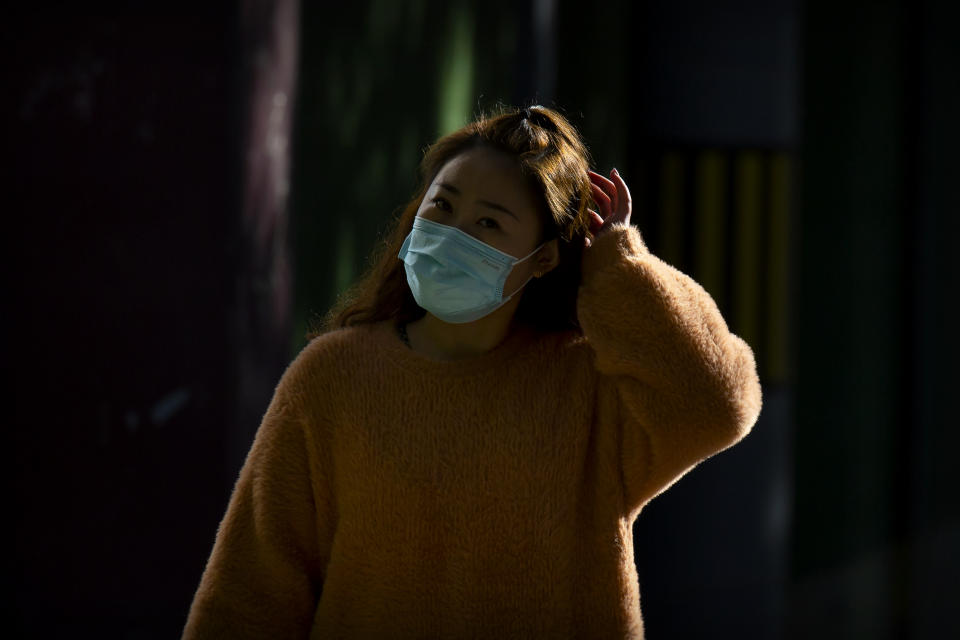 A woman wearing a face mask to protect against the coronavirus walks along a street in Beijing, Thursday, Oct. 22, 2020. The number of confirmed COVID-19 cases across the planet has surpassed 40 million, but experts say that is only the tip of the iceberg when it comes to the true impact of the pandemic that has upended life and work around the world. (AP Photo/Mark Schiefelbein)