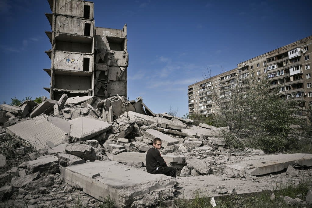 A boy sits amid shelled buildings in Kramatorsk in the eastern Ukranian region of Donbas (AFP via Getty Images)