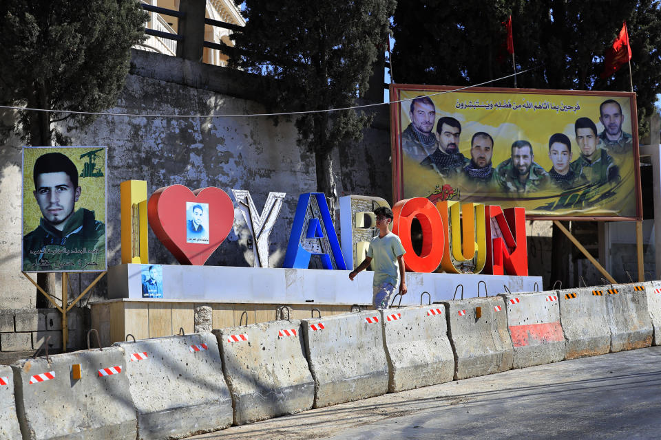 A Lebanese youth walks next to portraits of killed Hezbollah fighters in the Lebanese-Israeli border village of Yaroun, south Lebanon, Saturday, Aug. 13, 2022, where the parents of Hadi Matar emigrated from. On Friday, Matar, 24, born in Fairview, N.J., attacked author Salman Rushdie during a lecture in New York. His birth was a decade after "The Satanic Verses" was first published. (AP Photo/Mohammed Zaatari)