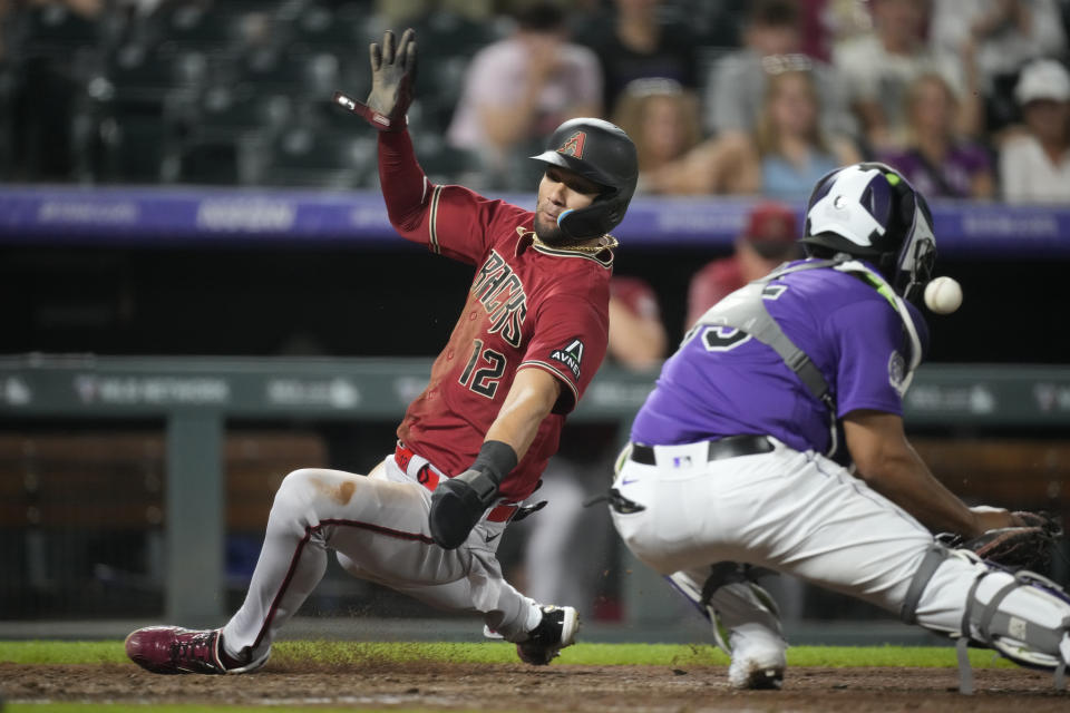 Arizona Diamondbacks' Lourdes Gurriel Jr., left, scores on a single by Jace Peterson as Colorado Rockies catcher Elias Diaz fields the throw from the outfield during the ninth inning of a baseball game Tuesday, Aug. 15, 2023, in Denver. (AP Photo/David Zalubowski)