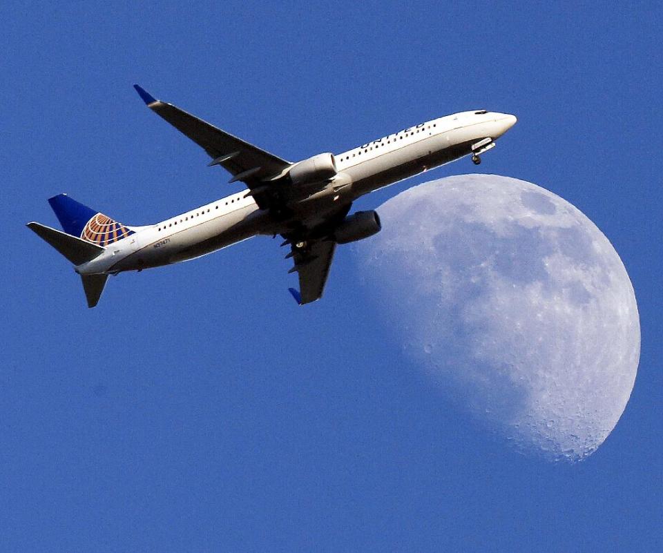 FILE - In this July 17, 2013 file photo, a United Airlines jet plane landing at Los Angeles International Airport, in Whittler City Calif., passes in front of a Waxing Gibbous moon. United Airlines reports quarterly earnings on Thursday, April 24, 2014. ( AP Photo/Nick Ut, File)