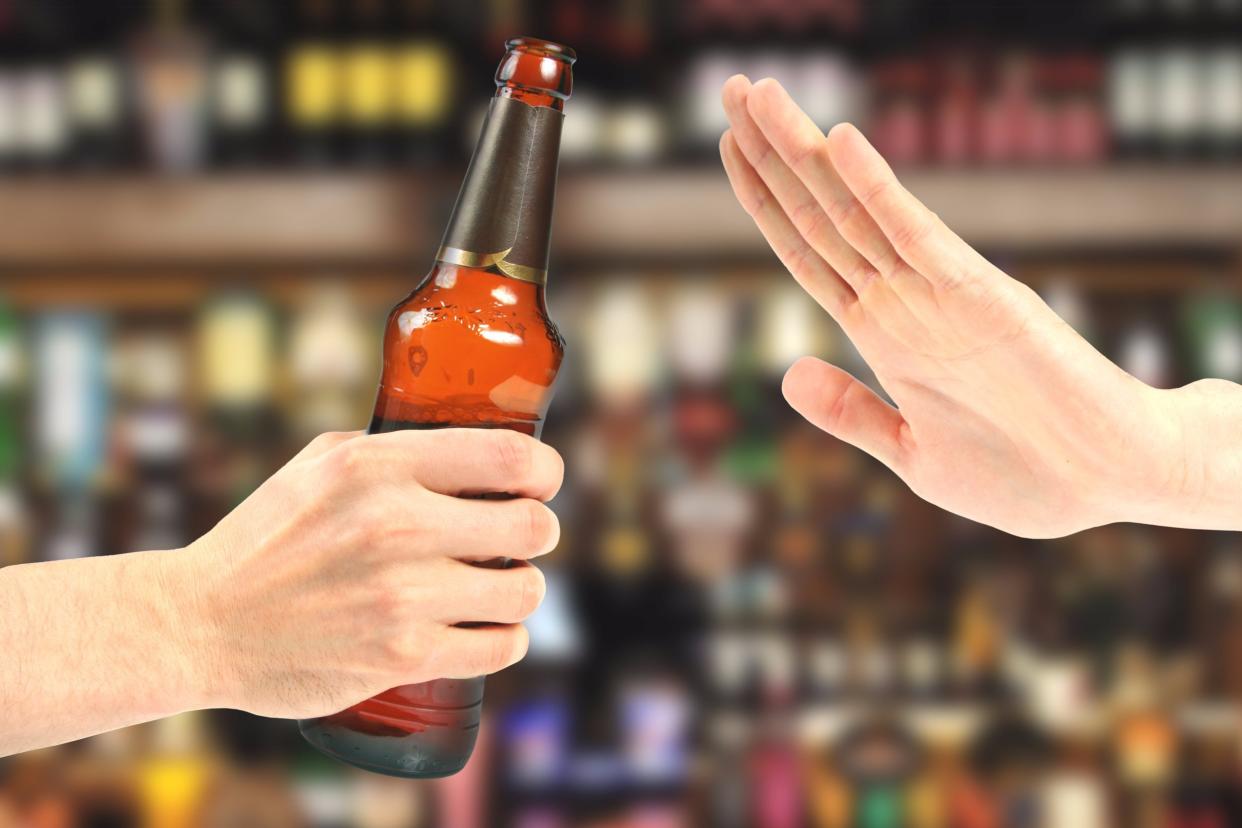 Hand rejecting a bottle of beer in the bar.