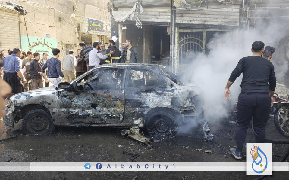 This photo provided by the Syrian anti-government activist group Albab City, which has been authenticated based on its contents and other AP reporting, people check the aftermath of a car bomb exploded in the city of al-Bab, northern Syria, Saturday, Nov. 16, 2019. A car bomb exploded Saturday in a northern Syrian town controlled by Turkey-backed opposition fighters, killing at least 18 people and wounding several others, Syrian opposition activists and Turkey's Defense Ministry said. (Albab City via AP)