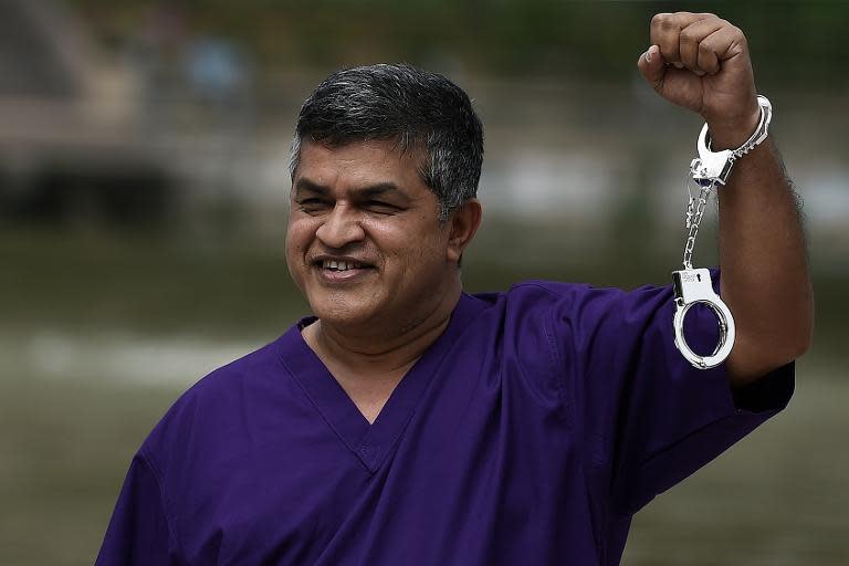 Malaysian cartoonist Zulkifli Anwar Ulhaque, popularly known as Zunar, poses with handcuffs prior to a book launch event in Kuala Lumpur, on February 14, 2015