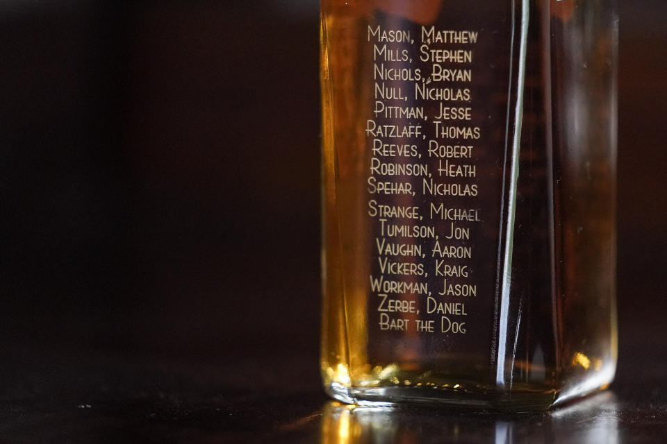 The names of servicemen who died when their Chinook helicopter was shot down in 2011 in Afghanistan are seen on a liquor bottle displayed by U.S. Army veteran Andrew Brennan, 36, in his home in Baltimore, on June 30, 2021. The former Army captain who flew combat missions in Afghanistan lost one of his closest friends, pilot Bryan Nichols, who was killed along with the entire crew when their Chinook helicopter was shot down in 2011, killing 30 Americans, seven Afghan soldiers and one interpreter. It was the single deadliest day for U.S. troops during the war. (AP Photo/Julio Cortez)
