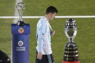 Argentina's Lionel Messi walks with his silver medal past the Copa America trophy (R) during the presentation ceremony after Chile defeated his team in the Copa America 2015 final soccer match at the National Stadium in Santiago, Chile, July 4, 2015. REUTERS/Ueslei Marcelino