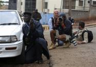 A policeman and photographers take cover after hearing gun shots near the Westgate shopping centre in Nairobi September 23, 2013. REUTERS/Karel Prinsloo