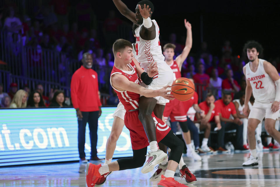 This photo provided by Bahamas Visual Services Wisconsin guard Connor Essegian passes around Dayton guard Kobe Elvis driving against Dayton guard Kobe Elvis (24) during an NCAA college basketball game at the Battle 4 Atlantis at Paradise Island, Bahamas, Wednesday, Nov. 23, 2022. . (Tim Aylen/Bahamas Visual Services via AP)