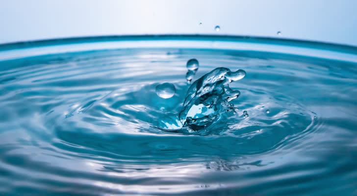 A zoomed in photo of a drop of water hitting a container of water's surface.