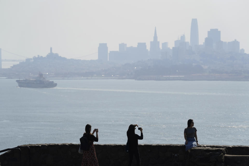 People take pictures at a vista point with the San Francisco skyline obscured by smoke from wildfires and heat in the background Monday, Sept. 28, 2020, near Sausalito, Calif. (AP Photo/Eric Risberg)