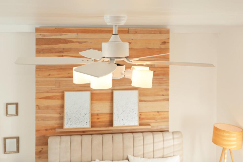 Modern ceiling fan in a bedroom with white and natural wood Scandinavian vibe.