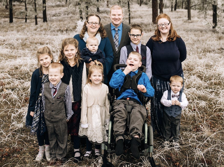 the tanner family, minus baby ezra, posing for a group photo in a wooded area