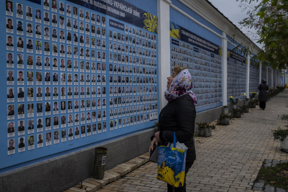 A woman stands in front of the "Memory wall of fallen defenders of Ukraine in Russia-Ukranian war" in downtown Kyiv, Ukraine, Monday, Nov. 7, 2022. (AP Photo/Bernat Armangue)