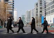 Security personnel wearing masks cross a road at the Financial Street in central Beijing