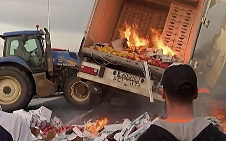 French farmers set a lorry on fire and push it over with a tractor
