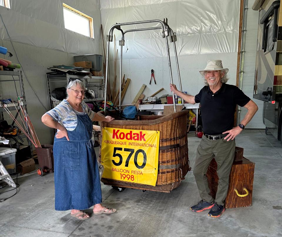 Toni and Bill Woodman pose by their basket "Cy in the air" hot air balloon, which they store in a large garage on their property near Ames.