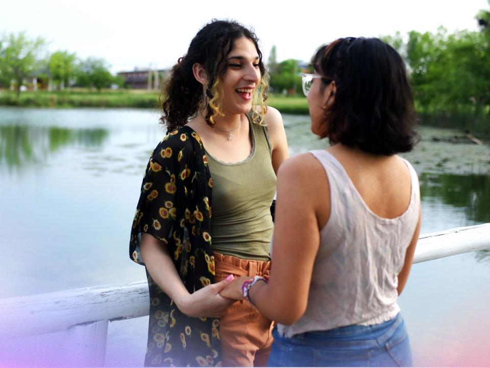 two women talking to each other on a bridge over a lake