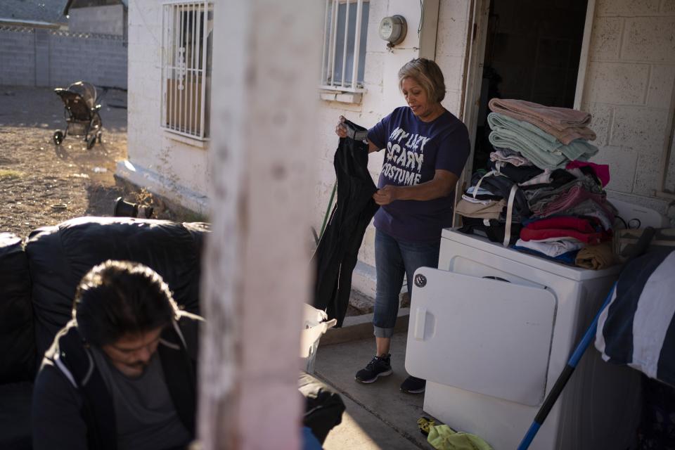 Norma Flores, 54, folds the laundry while her son works on his bicycle at their home in Henderson, Nev., Tuesday, Nov. 10, 2020. Flores is a Mexican immigrant who spent two decades working as a waitress at the Fiesta before COVID-19 descended and she lost her job. Now, her empire is a concrete block house crowded with six grandchildren, most of them doing school online. She dreads when she overhears a teacher asking what students had for their lunches and snacks. She rarely has enough food for both. (AP Photo/Wong Maye-E)