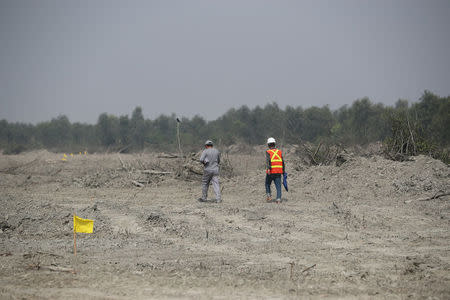 Construction workers walk along the Vashan Char, previously known as Thengar Char island in the Bay of Bengal, Bangladesh February 14, 2018. Picture taken February 14, 2018. REUTERS/Stringer