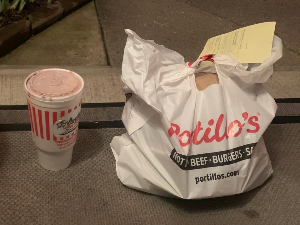 portillos shake and bag of food on someone's front porch next to a pumpkin decoration