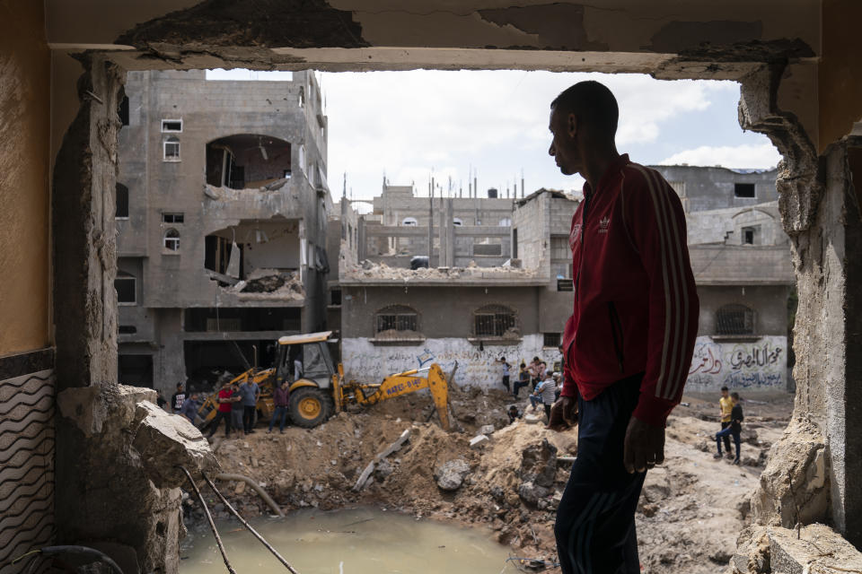 Nader al-Masri, a long-distance runner who participated in dozens of international competitions, including the 2008 Olympics, stands inside his severely damaged home beside the crater where the home of Ramez al-Masri was destroyed by an air-strike prior to a cease-fire reached after an 11-day war between Gaza's Hamas rulers and Israel, Sunday, May 23, 2021, in Beit Hanoun, the northern Gaza Strip. (AP Photo/John Minchillo)