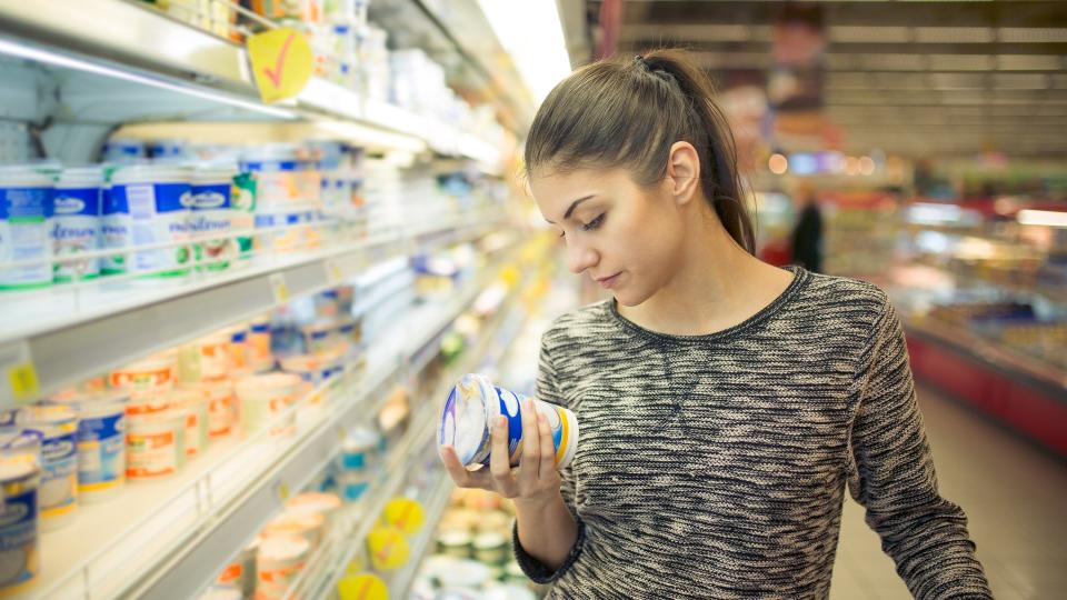 girl reviewing expiration date on food in store