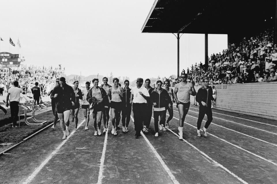 Oregon Track and Field Coach Bill Bowerman, center, runs a victory lap with members of his team after they won the 1964 NCAA Championships.