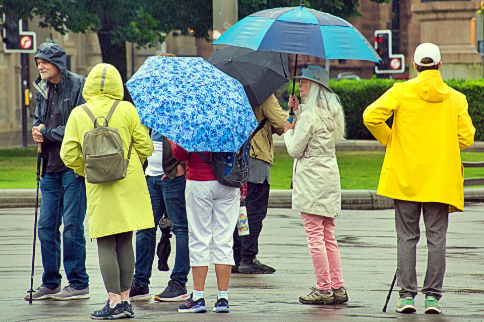 Glasgow, Scotland, UK. 16th July, 2024: UK Weather: Tourist history walking tours suffer weather around george square. Rain saw tourists and locals in the city centre dive for their umbrellas in the showers with a forecast for more. Credit Gerard Ferry/Alamy Live News