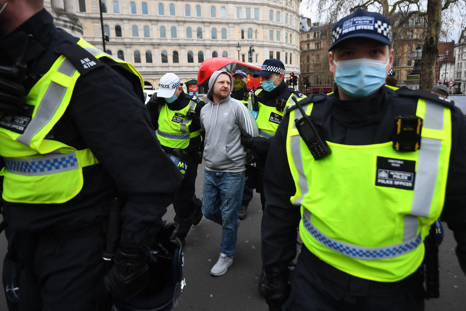 Police detain a man as people take part in an anti-lockdown protest in Trafalgar Square, central London. Picture date: Saturday March 20, 2021.