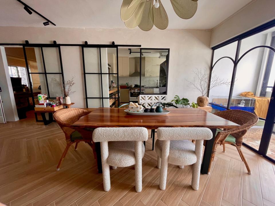 A view of the dining area with a large wooden dining table and a door leading to the balcony on the right.