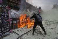 A demonstrator throws burning gasoline at a police shield wall that is closing a breach on a barricade protecting the National Palace during a march to commemorate International Women's Day and protest against gender violence, in Mexico City, Monday, March 8, 2021. (AP Photo/Ginnette Riquelme)