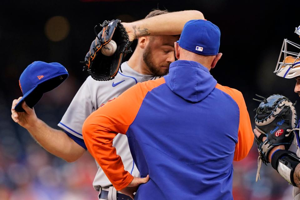 New York Mets starting pitcher Tylor Megill, left, wipes his face as he listens to pitching coach Jeremy Hefner during the first inning of a baseball game at Nationals Park, Wednesday, May 11, 2022, in Washington.