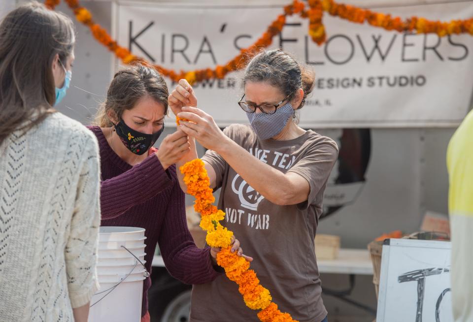 Teresa Brockman, right, and her daughter Kira Santiago, owner of Kira's Flowers, string together a garland of African marigolds at their booth Saturday, Sept. 26, 2020, on the last day of the season for the weekly Peoria Riverfront Market.