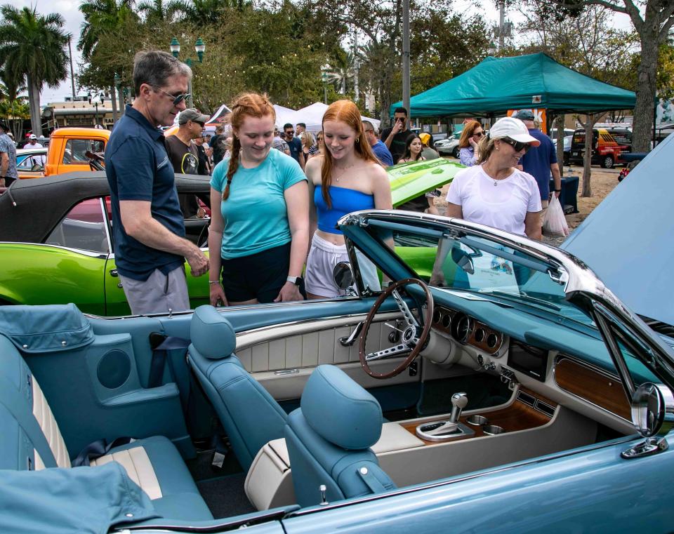 A family checks out a 1966 Ford Mustang entered in the Muscle on the Beach Car Show on Saturday at Old School Square in Delray Beach..