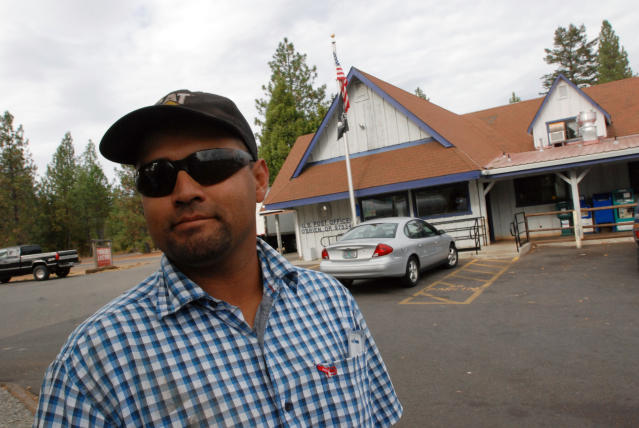 In this Oct. 12, 2012, photo, Hector Guzman poses for a photo in front of the post office in O'Brien, Ore., where cuts to sheriff's patrols prompted by the failure of a tax levy have inspired some local residents to organize armed patrols of the rural area of about 750 residents. Guzman, whose home was burglarized several years ago, said he likes the idea of people watching out for each other. (AP Photo/Jeff Barnard)