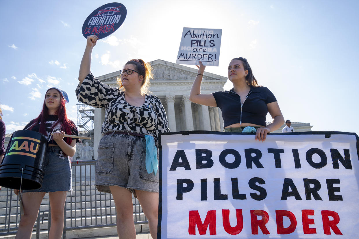 Staff with the group, Progressive Anti-Abortion Uprising, Kristin Turner, of San Francisco, left, Lauren Handy, of Washington, and Caroline Smith, of Washington, right, demonstrate against abortion pills outside of the Supreme Court, Friday, April 21, 2023, ahead of an abortion pill announcement by the court in Washington. (AP Photo/Jacquelyn Martin)