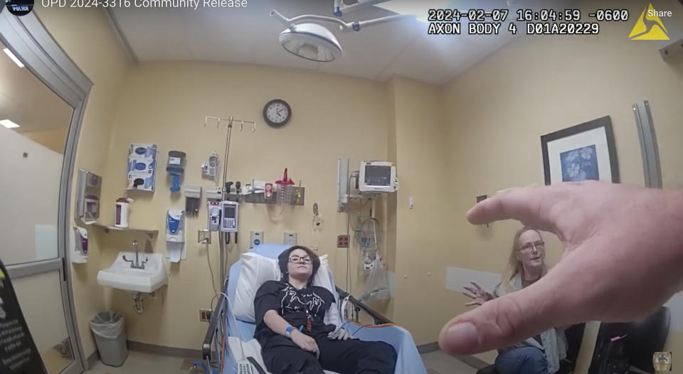 In this frame grab taken from body camera video provided by the Owasso, Okla., Police Department, an officer, hand at right, speaks to 16-year-old Nex Benedict, left, and their mother, Sue Benedict, at a hospital, Wednesday, Feb. 7, 2024. Sue says that Nex was knocked to the floor during a fight in a school bathroom earlier in the day. Nex died the following day. (Owasso Police Department via AP)