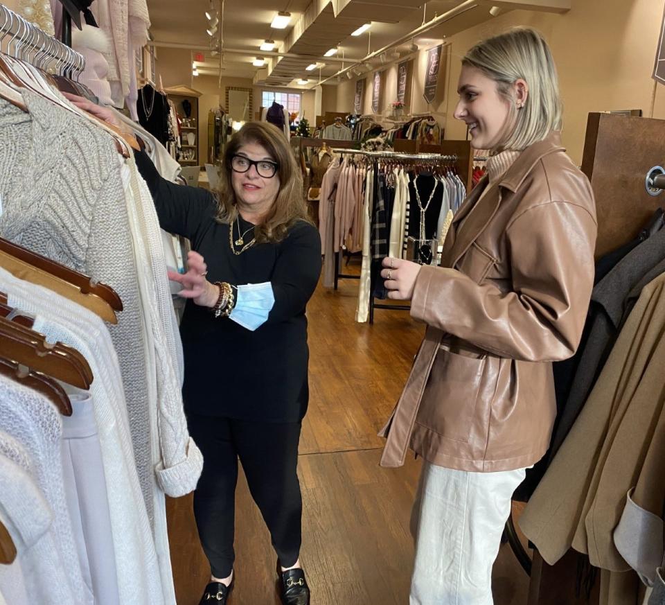 Leal Boutique sales associate Marisa Cinson (left) shows sweaters to Anna Johnson on Dec. 1 at the shop. Cinson recently received a $300 bonus through a JumpStart UA program in which the city of Upper Arlington is using federal funds to help small businesses thank and retain employees.