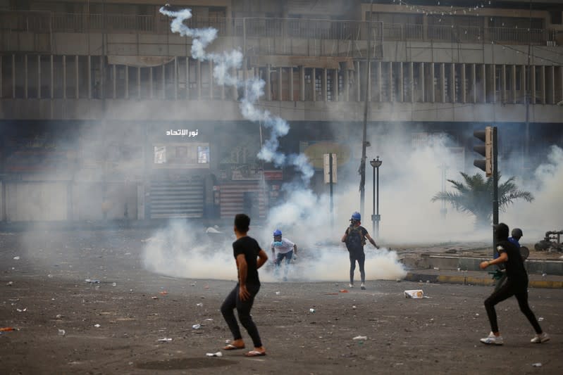 A demonstrator throws away a tear gas canister during the ongoing anti-government protests in Baghdad