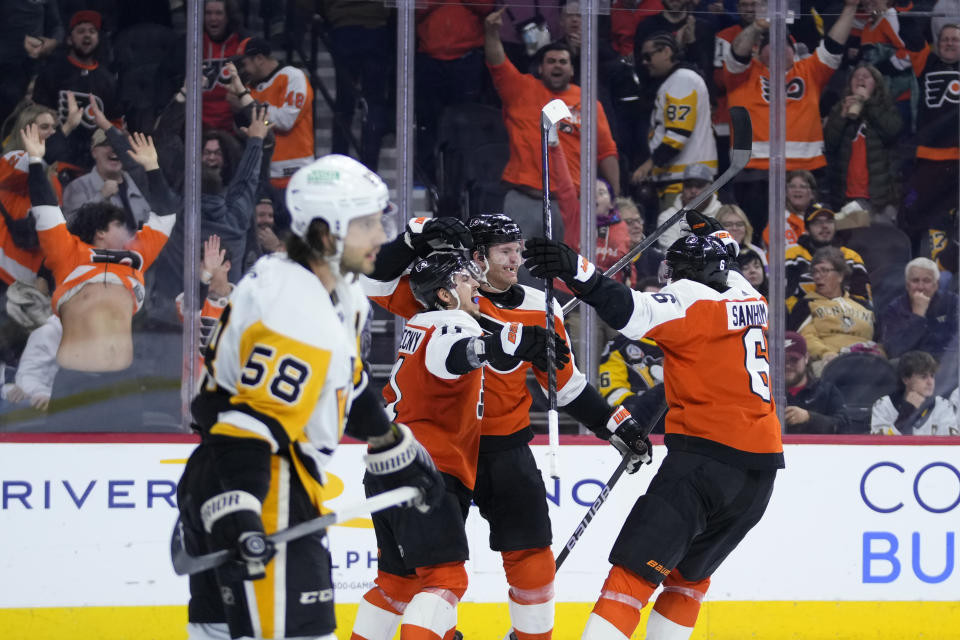 Philadelphia Flyers' Travis Sanheim, from right, Sean Couturier and Travis Konecny celebrate past Pittsburgh Penguins' Kris Letang after Couturier's game-winning goal during overtime in an NHL hockey game, Monday, Dec. 4, 2023, in Philadelphia. (AP Photo/Matt Slocum)