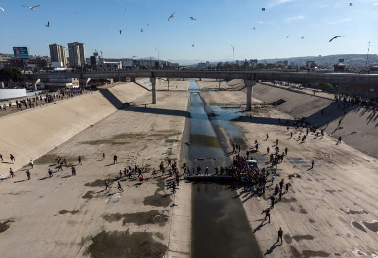 A group of Central American migrants -- mostly from Honduras -- cross the almost dry riverbed of the Tijuana River in an attempt to get to El Chaparral port of entry, in Tijuana, Mexico, on November 25, 2018