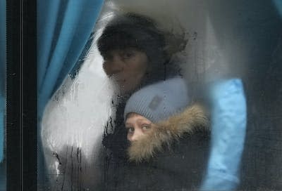 Una mujer y un niño miran por la ventanilla de un autobús al salir de Sievierodonetsk, en el este de Ucrania, en febrero de 2022. (AP Photo/Vadim Ghirda)