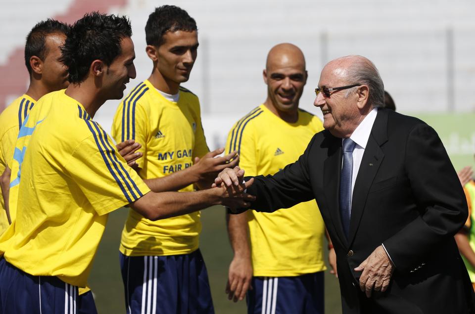 FIFA President Sepp Blatter (R) shakes hands with Palestinian coaches as he visits a football academy named after him, near the West Bank city of Ramallah May 27, 2014. REUTERS/Mohamad Torokman (WEST BANK - Tags: POLITICS SPORT)