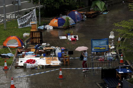 A passerby walks past tents, before they are removed, outside the government headquarters in Hong Kong, China June 24, 2015. REUTERS/Bobby Yip