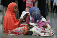 Girls read the Holy book the Quran after arriving for the jenazah. REUTERS/Lucy Nicholson