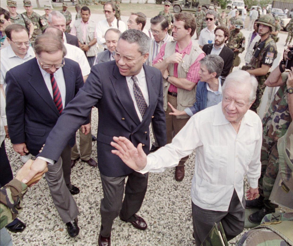 From left, Sen. Sam Nunn, retired Gen. Colin Powell and former President Jimmy Carter, and wave to the media on Feb. 24, 1995, in Port-au-Prince, Haiti, before attending a military briefing on the current situation in Haiti. Later today the trio will travel to several areas of the countryside.
