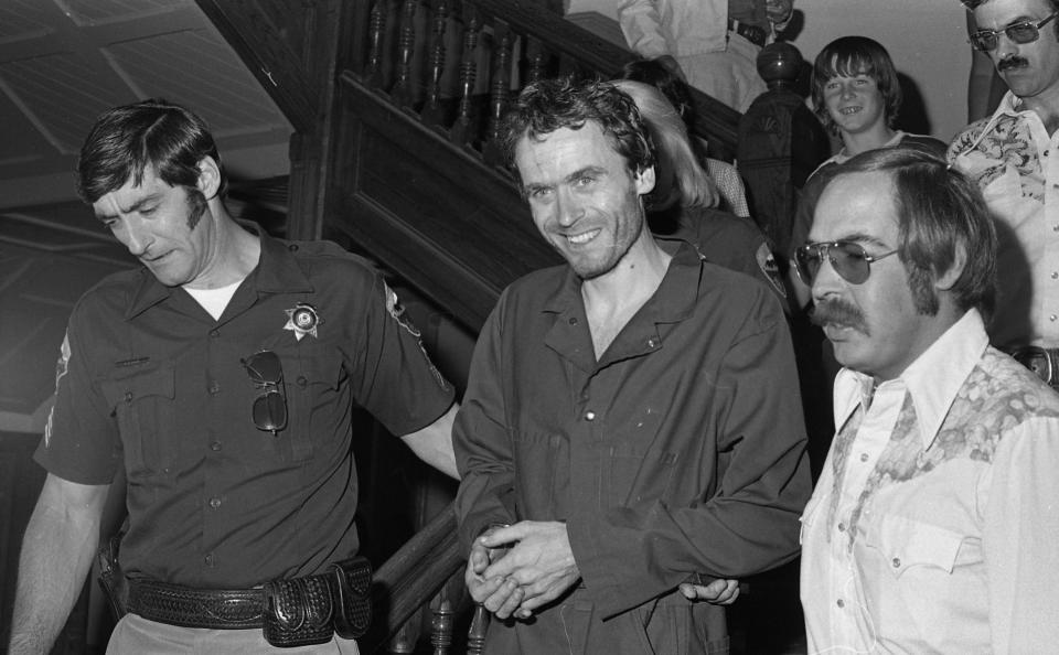 FILE - In this 1977 file photo, serial killer Ted Bundy, center, is escorted out of court at the Pitkin County courthouse, Aspen, Colo. In 2017, the Glenwood Springs Post-Independent re-discovered the 40-year-old photo of Bundy, along with others, that had been locked in an old newsroom safe, which a local locksmith volunteered to open. The pictures show Bundy in custody in 1977, the year he escaped from local law enforcement twice while awaiting a murder trial. (Ross Dolan/Glenwood Springs Post Independent via AP)